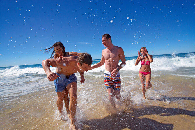 Group of young adults playing and laughing in the surf at Kurrawa Beach—one of the top attractions around Gold Coast for relaxed beach fun and coastal energy.