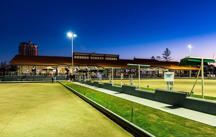 Evening at Broadbeach Bowls Club with people playing barefoot bowls under lights—an inviting local spot when deciding what to do in Broadbeach for a relaxed afternoon.